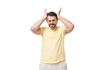 Wall Mural - young brutal brunette man in a t-shirt feels a headache on a white background with copy space