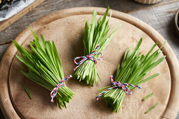 Wall Mural - Three bundles of fresh young green barley grass blades on a table