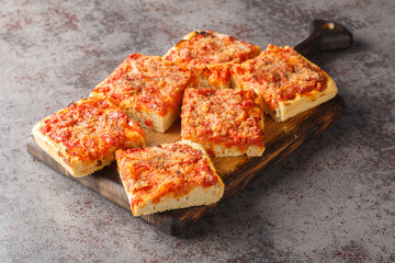 Wall Mural - Sfincione typical oven-baked focaccia very soft and seasoned with tomato, onion, anchovies, cheese, oregano and bread crumbs closeup on the wooden board on the table. Horizontal