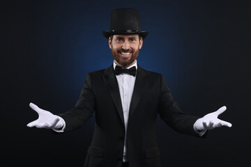 Wall Mural - Happy magician in top hat on dark blue background