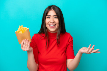 Wall Mural - Young caucasian woman catching french fries isolated on blue background with shocked facial expression