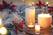 Cozy winter composition with burning candles and Christmas decor details.