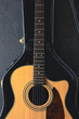 Acoustic guitar in a protective case on a dark background, top view.