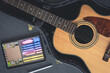 Acoustic guitar and digital tablet with a music application, top view.