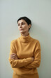 © Westend61 - Pensive woman in yellow turtle-neck crossing hands on chest
