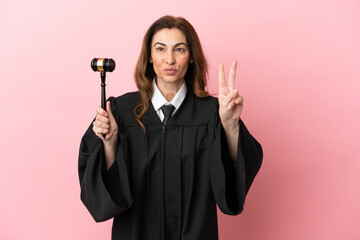 Wall Mural - Middle aged judge woman isolated on pink background smiling and showing victory sign