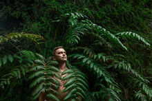 Shirtless Man With Eyes Closed Standing Amidst Fern Plants