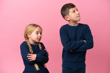 Wall Mural - Little caucasian brothers isolated on pink background making doubts gesture while lifting the shoulders