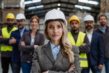 Full team of warehouse employees standing in warehouse. Team of workers, managers, female director in modern industrial factory, heavy industry, manufactrury.