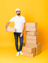 Wall Mural - Full-length shot of delivery man among boxes over isolated yellow background with sad and depressed expression