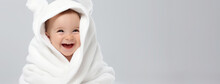 Smiling Baby Infant Wrapped In White Furry Blanket. Portrait Of Happy Adorable Caucasian Little Boy Wrapped In Fluffy Towel After Bath Against Light Gray Background. Textiles And Bedding For Children
