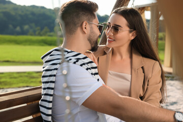 Wall Mural - Romantic date. Beautiful couple spending time together on swing bench outdoors