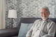 © Daniel - Portrait of happy mature 80s man sit on couch at home look at camera posing relaxing on weekend, smiling positive senior 70s grandfather rest on sofa at home or retirement house, show optimism.