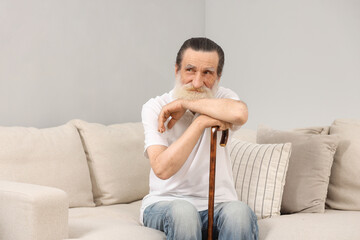 Wall Mural - Senior man with walking cane on sofa indoors