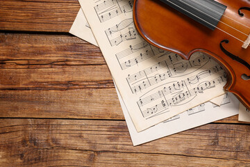 Sticker - Violin and music sheets on wooden table, top view. Space for text