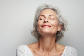 Portrait of a happy senior woman with closed eyes against grey background