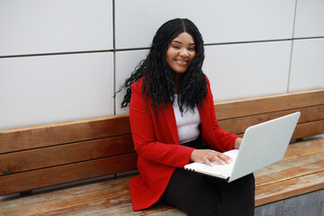 Wall Mural - beautiful african woman in red jacket working with laptop