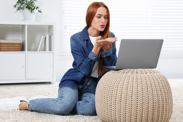 Wall Mural - Woman blowing kiss during video chat via laptop at home. Long-distance relationship