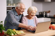© AspctStyle - Mature married couple sitting together with laptop on the kitchen at home, modern happy senior man and woman look at laptop screen