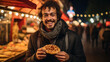 Young man eating hot dog while standing at Christmas market