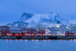 Typical Lofoten village just before sunrise with red houses and snowy mountain in the background