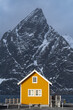 Typical Lofoten wooden yellow house with black big mountain in the background