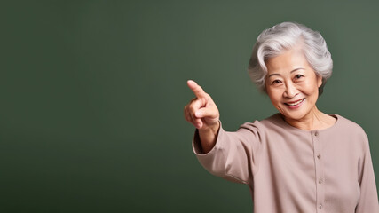 Wall Mural - Happy senior asian woman point her finger at copy space for promotion