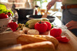 © Marko Geber - Fresh vegetables on kitchen countertop with woman cooking at home
