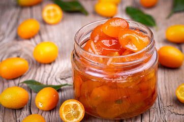 Wall Mural - Homemade kumquat jam in jar and fresh kumquats, top view