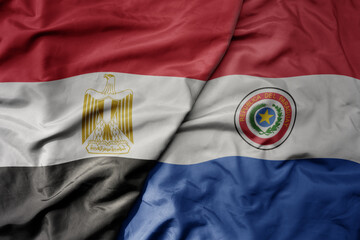 big waving national colorful flag of paraguay and national flag of egypt .