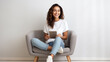 © MP Studio - Woman sits on the chair and smiles holding her smartphone in her hands