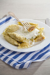 Wall Mural - cooked dumplings with meat, spices and sour cream, in a plate on a light wooden table.