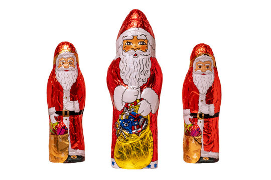 Chocolate Santa isolated. Close-up of three cheerful wrapped chocolate Santa Claus or the good Saint Nicolas figurine isolated on a white background. Macro photograph.