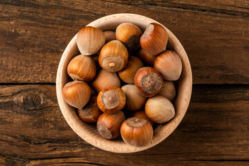 Wall Mural - Overhead shot of hazelnuts in bowl on wooden table. Healthy snacks