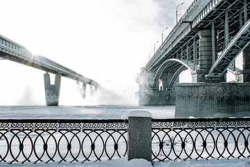 Wall Mural - Bridge is over frozen river. Embankment of the Ob river in winter in Novosibirsk frost day -40 degrees Celsius