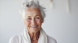 Fototapeta  - Portrait of a happy elderly senior woman looking at the camera on a white bright blurred studio background