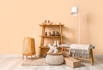 Wall Mural - Shelving unit with different stylish female shoes, bench and lamp near beige wall in room