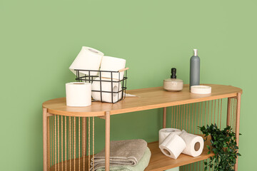 Wall Mural - Wooden rack with toilet paper rolls, clean towels and cosmetic products near color wall