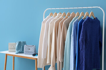 Wall Mural - Rack with stylish clothes and bags near color wall
