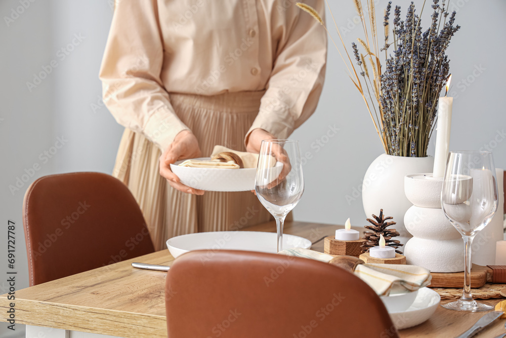Woman setting table with dried flowers in dining room