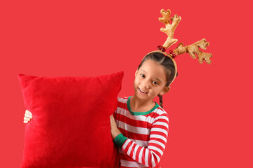 Wall Mural - Cute little girl with Christmas cushion on red background