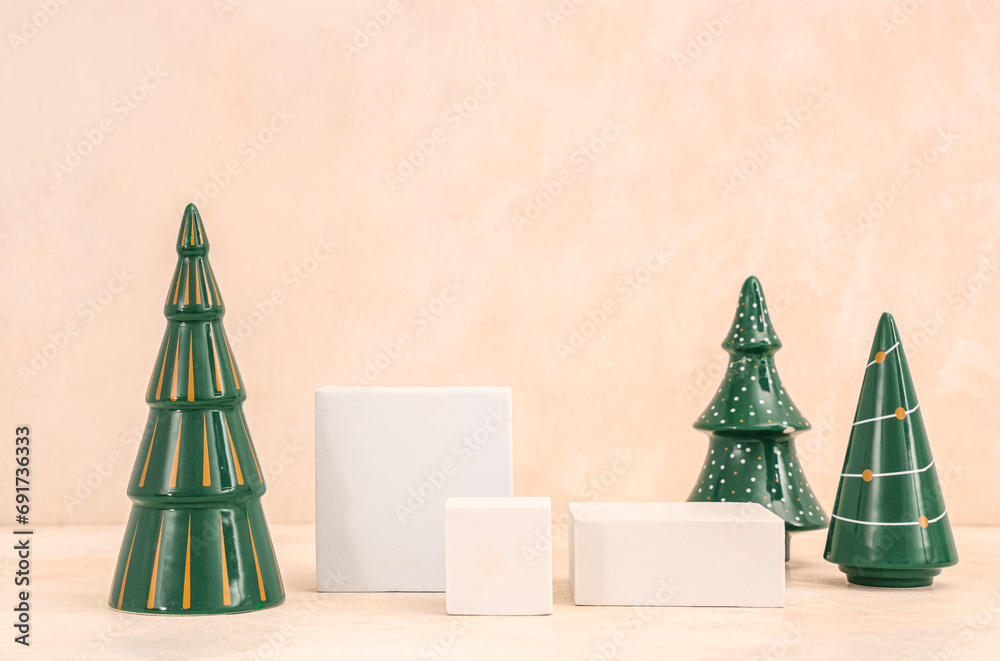 Decorative Christmas trees with plaster podiums on beige grunge background