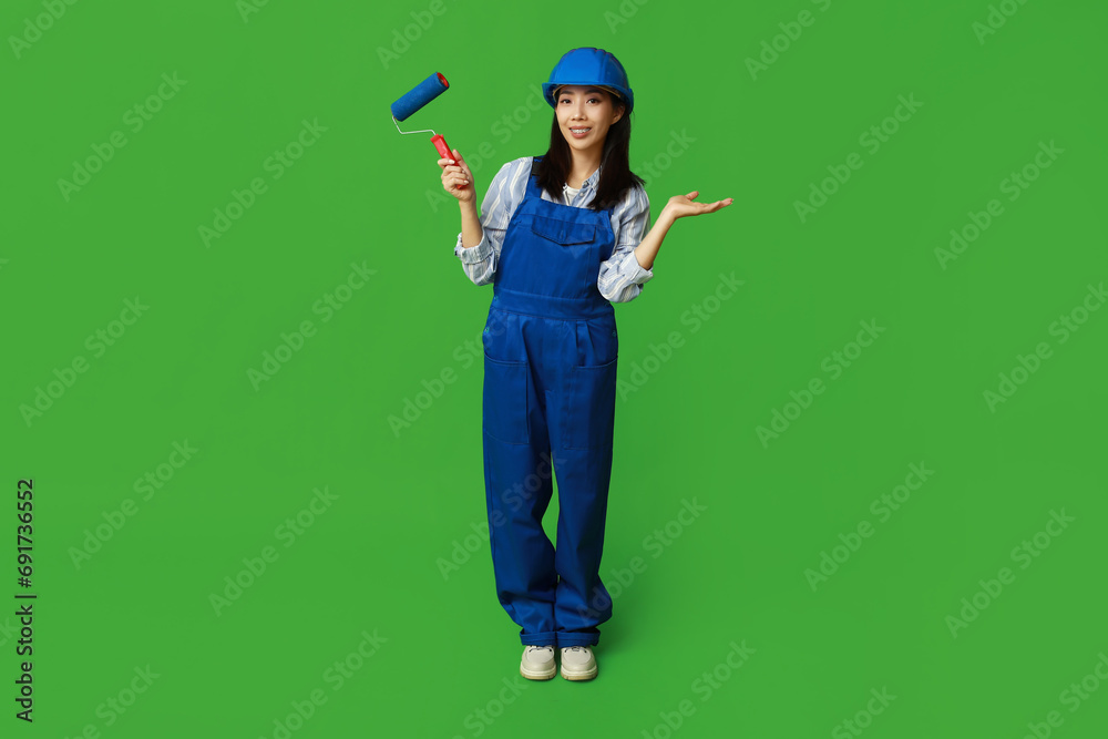 Female Asian painter with roller on green background