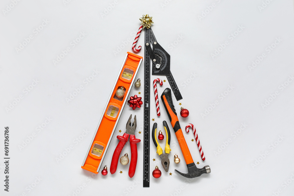 Christmas tree made of construction tools and decorations on light background