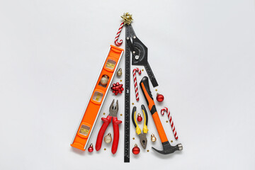 Christmas tree made of construction tools and decorations on light background