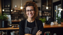 A Cheerful Woman With A Bright Smile Stands Behind The Bar, Her Glasses Perched On Her Nose And An Apron Tied Around Her Waist, Ready To Serve A Refreshing Bottle Of Drinks Against A Colorful Wall Ba