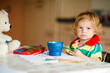 © Irina Schmidt - Cute adorable baby girl learning painting with water colors. Little toddler child drawing at home, using colorful brushes. Healthy happy daughter experimenting with colors, water at home or nursery.