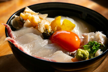 Wall Mural - Japaneses sashimi donburi with white fish, squid and egg yolk on a bed of white rice.