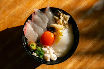 Wall Mural - Japaneses sashimi donburi with white fish, squid and egg yolk on a bed of white rice.