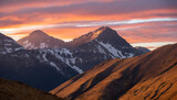 Fototapeta Fototapeta z niebem - Kolorowe niebo w odcieniach pomarańczy i różu, zachodzące słońce odbijające się od szczytów gór